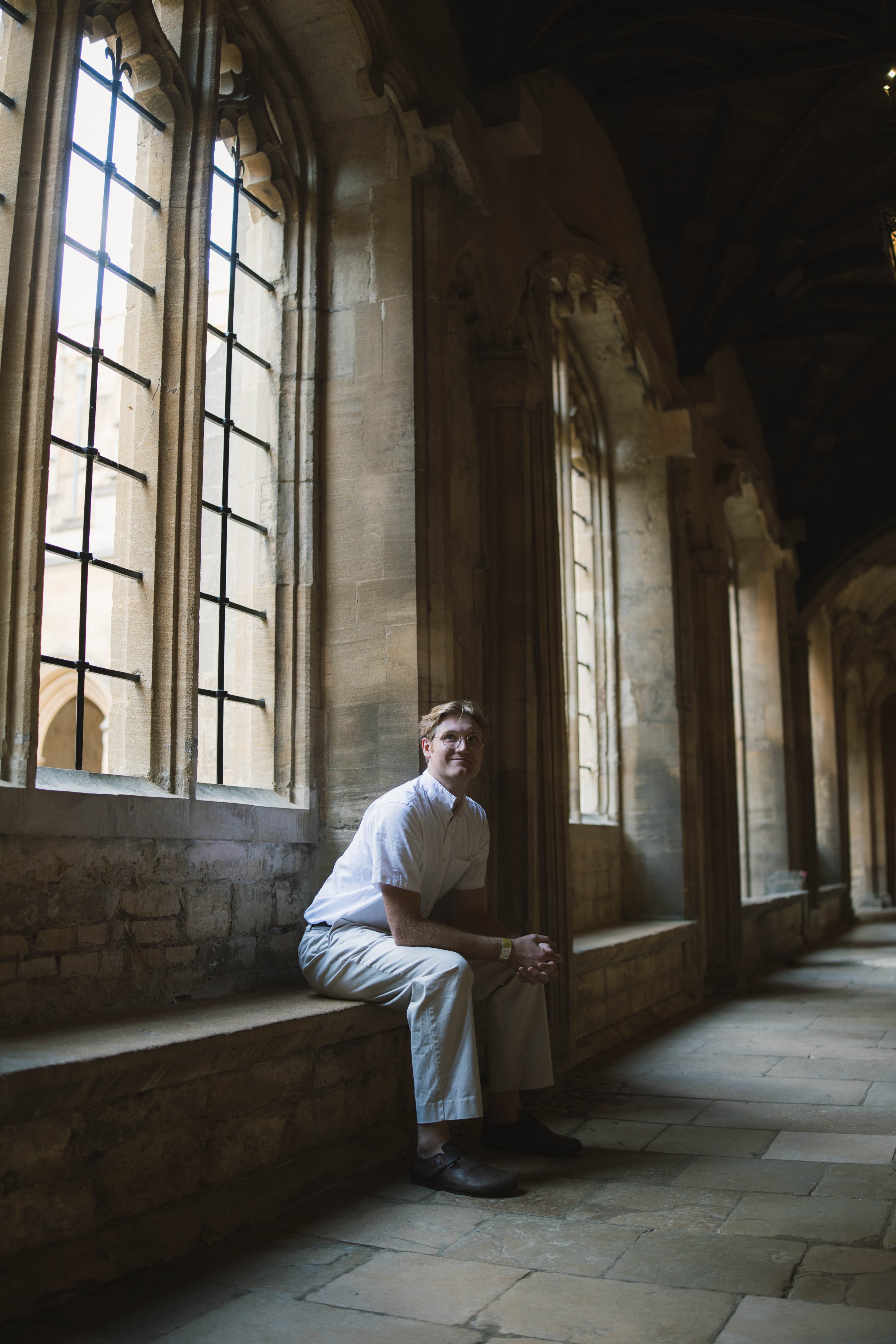 Enoch seated on a stone window ledge in a cloister